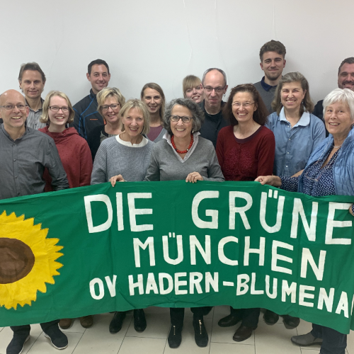 Gruppe von OV-Mitgliedern, die ein Grüns Tuch mit dem Text Die Grünen München OV Hadern-Blumenau sowie einer gemalten Sonnenblume halten.